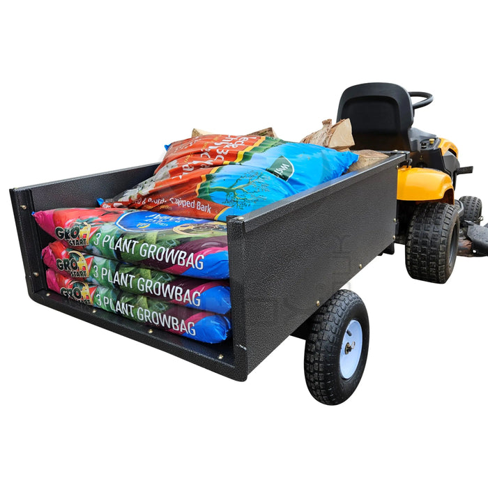 A lawn mower with an Iron Ox® 'MT' - Tipping Trailer 400lb attached and a dump cart on it.