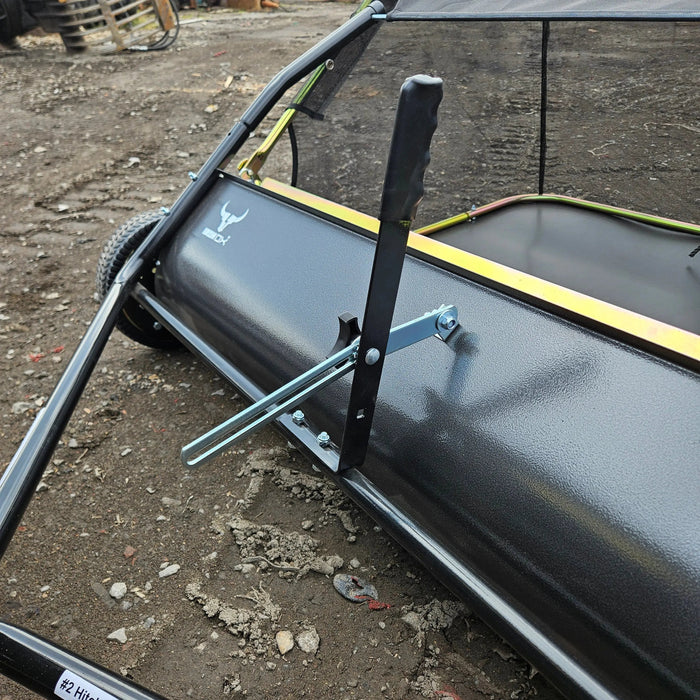 Close-up of the 48" Tow-Behind Lawn Sweeper—Heavy-Duty Leaf, Grass & Debris Collector for Riding Mowers, Tractors & ATVs—with adjustable brush height, shown on dirt and gravel.