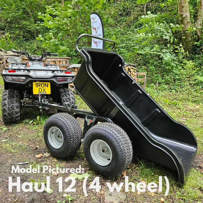 An Iron Ox® Haul 12 Tipping Trailer 1200lb 4-Wheel with a corrosion-resistant bed is hitched to an ATV in a wooded outdoor setting.