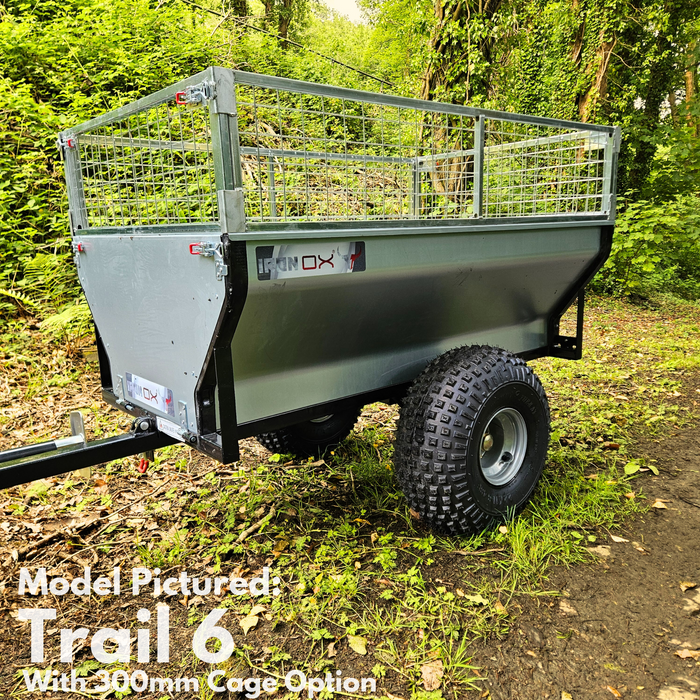 A rugged All-Terrain ATV & Farm Tipping Trailer | Heavy-Duty Utility Trailer - Trail 6 with 900mm mesh cage sides and large off-road tires is parked on a dirt path in a wooded area—ideal for tough adventures.