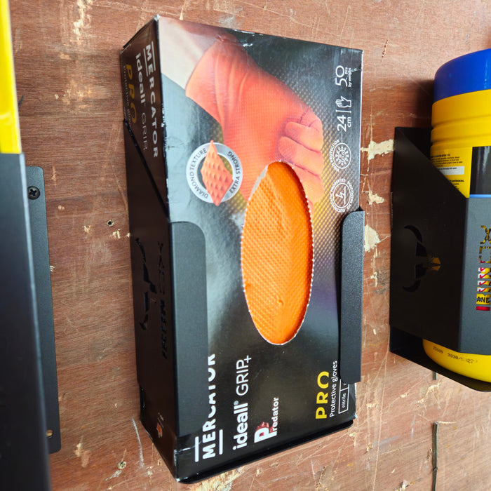 A box of medium-sized orange latex grip gloves in a Rubber Glove Dispenser Holder on a wooden shelf next to a yellow tool.