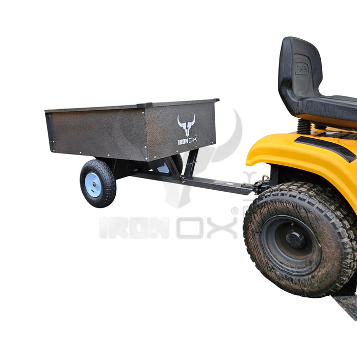 A yellow lawn mower with an Iron Ox® 'MT' - Tipping Trailer 400lb attached to it, featuring a dump cart for convenient transport.