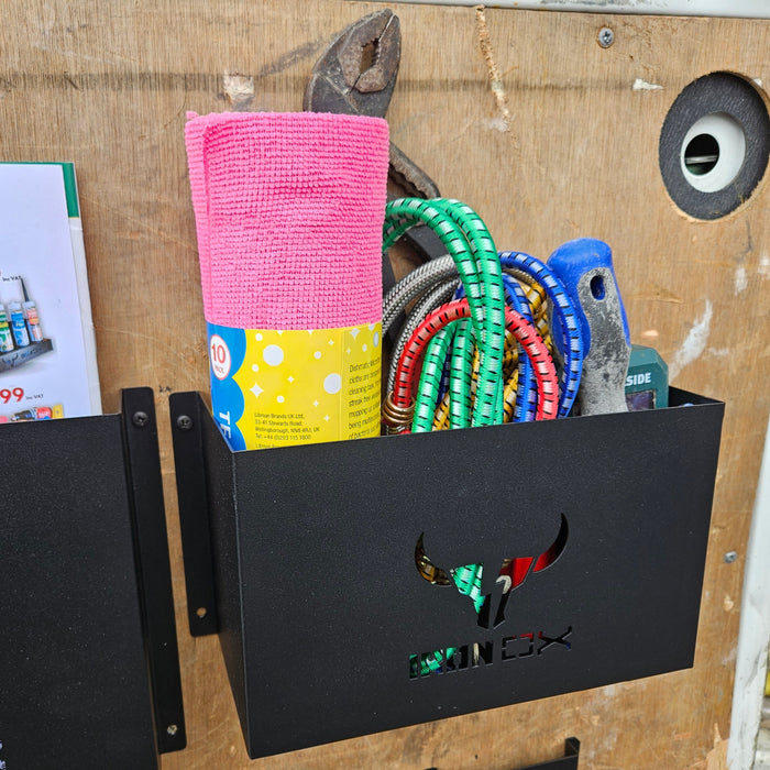 A collection of fitness equipment, including a jump rope, hand grip, and towel, stored in a General Purpose Metal Storage Box - Medium affixed to a wooden wall.