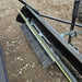 Close-up of the underside of the Tow-Behind Lawn Sweeper 48", showing its rotating brush with adjustable height and durable metal frame, designed for heavy-duty leaf, grass, and debris collection with mowers or ATVs.