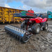 An efficient red Towable Spiked Roller Aerator 60" Wide sitting in the mud.