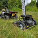 Quad bike towing a topper mower across a field during pasture maintenance.