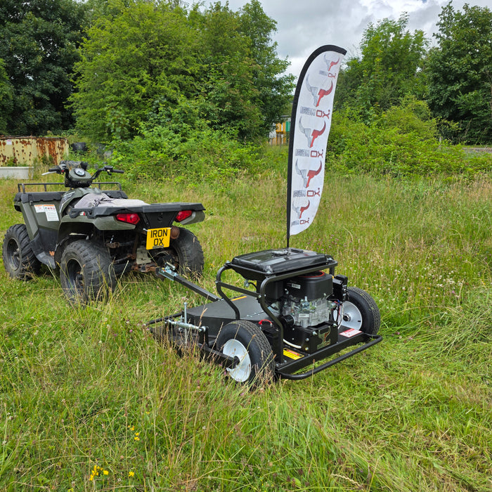 Heavy-duty tow behind topper mower attached to a quad bike cutting rough grass.