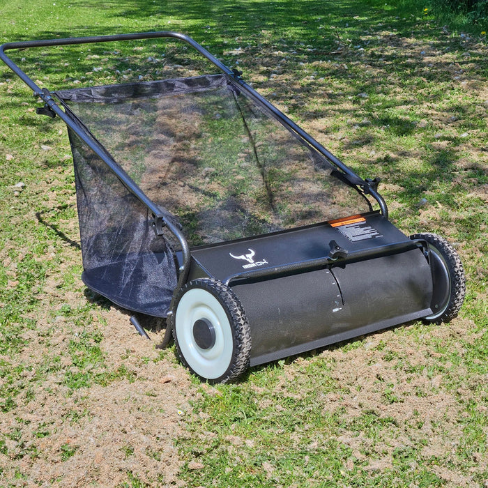 "Manual lawn sweeper collecting leaves on a backyard lawn"

