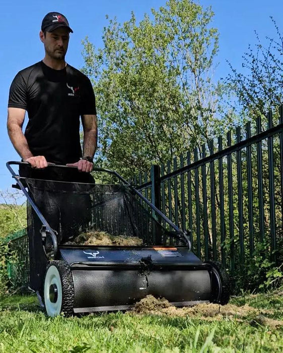 Push-style lawn sweeper in use, collecting grass clippings and leaves