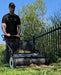 Push-style lawn sweeper in use, collecting grass clippings and leaves