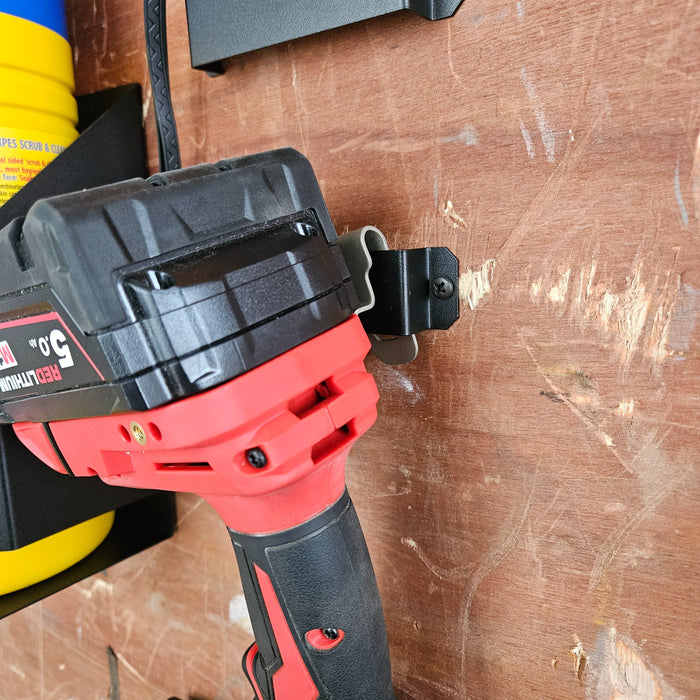 A cordless drill hung on a board with a storage hook, featuring a CNC Laser Cut Tape Measure Holder - 5 Pack.