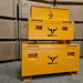Two yellow IronOx Contractors Van & Site Tool Chest Boxes, 45", are stacked in a warehouse amid IronOx-branded cardboard boxes, providing anti-theft protection for valuable equipment.